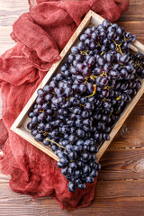 Photo of black grapes in wooden box with claret cloth