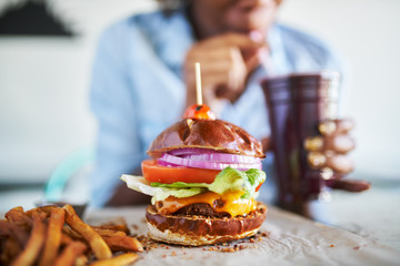 vegan meatless burger meal with african american woman drinking smoothie in background