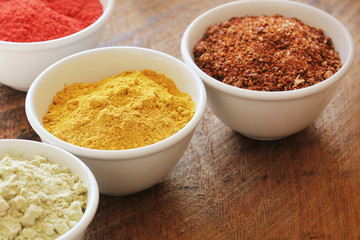 Various colorful spices on wooden table in bowls