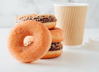Paper cup of coffee with tasty donuts on white background.