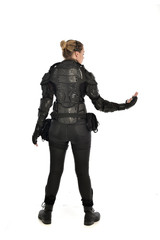 full length portrait of female  soldier wearing black  tactical armour  facing away from camera, isolated on white studio background.