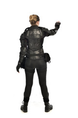 full length portrait of female  soldier wearing black  tactical armour  facing away from camera, isolated on white studio background.