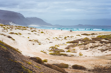 Deserted beach of Praia Grande. Spectacular sand dunes, ocean waves and black volcanic mountains behind. North of Calhau, Sao Vicente Island Cape Verde
