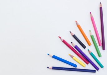 Old multicolored pastel pencils lay on grainy white drawing paper,top viwe shot.
