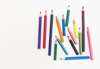 Beauty multicolored crayon pencils on white grainy drawing paper, top view shot.