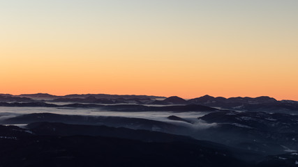 Obraz premium A frozen morning on top of Ciucas mountains in Romania with some beautiful clouds dancing in the valley bellow