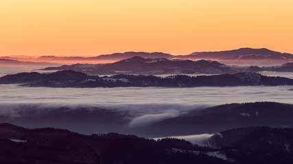 A frozen morning on top of Ciucas mountains in Romania with some beautiful clouds dancing in the valley bellow