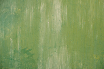 Textured metal surface carelessly colored green paint and faded in the sun in pale gray with rusty specks.