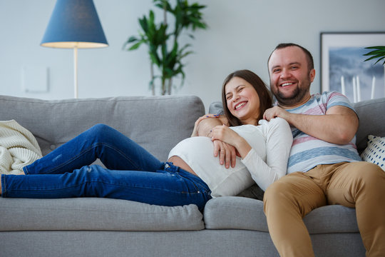Photo of happy married couple on gray sofa
