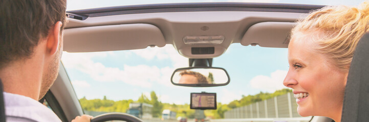 Car summer road trip couple having fun on travel vacation driving in convertible sports car. Blonde woman portrait happy smiling at man driver driving banner panorama.