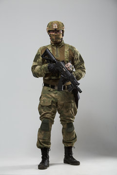 Full-length picture of military man in camouflage with gun