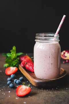 Strawberry smoothie in a jar with drinking straw