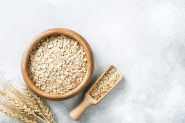 Rolled oats in wooden bowl on grey background with copy space