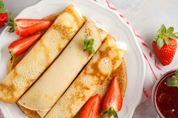 Thin hot pancakes with cottage cheese, jam and strawberries. Top view, copy space. Healthy traditional breakfast concept.