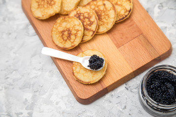 Russische Blinis mit Seehasen Kaviar auf Holzbrett mit Perlmuttlöffel