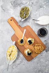 Obraz na płótnie Canvas Schwarzer Kaviar auf Perlmuttlöffel mit Pfannkuchen, Eier Hack, Saure Sahne und Relish 