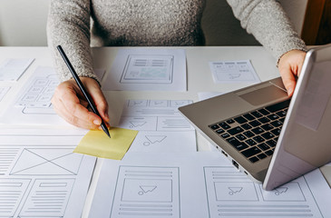 Web designer working at laptop and website wireframe sketches on white table © maicasaa