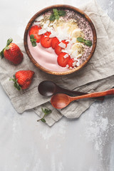 Strawberry pink smoothie bowl with banana, coconut and chia seeds, top view, copy space. Healthy vegan food concept.