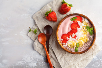 Strawberry pink smoothie bowl with banana, coconut and chia seeds, top view. Healthy vegan food concept.