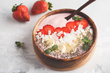 Strawberry pink smoothie bowl with banana, coconut and chia seeds. Healthy vegan food concept.