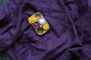 Chicken egg and flowers in carton on textile background