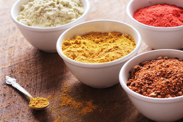 Various colorful spices on wooden table in bowls . Food and cuisine ingredients.