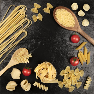 Overhead square photo of different types of pasta with cherry tomatoes on black
