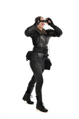 full length portrait of female  soldier wearing black  tactical armour  holding  a pair of binoculars, isolated on white studio background.