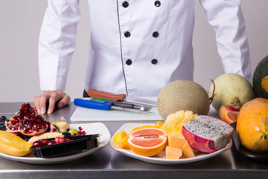 Chef preparing fruits for fruit salad over white background