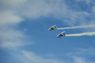 Two vintage single engine propeller biplanes aircrafts flying away and smoking