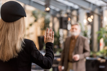 back view of woman waving to man in restaurant