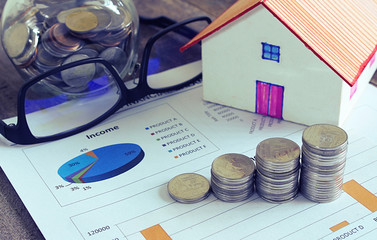 House model and book bank account and coin stack and data income sheet.