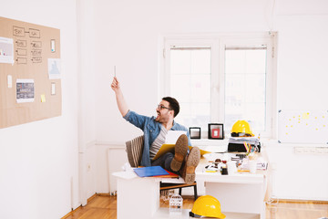 Young excited happy modern business man celebrating after getting ideas for problem-solving while holding legs on the office desk.