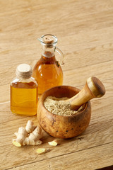 Composition of oil jars, wooden mortar and pestle with ginger and spices on rustic table, close-up, selective focus