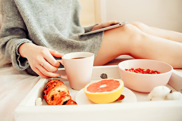 Breakfast and morning news- women reading morning news on her tablet in bed
