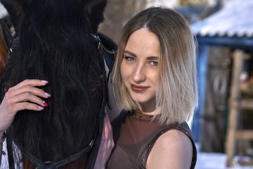 A girl with long blonde hair communicates with her favorite horse. The girl loves animals. Sunny...