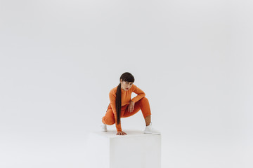 woman in orange clothes on white cube