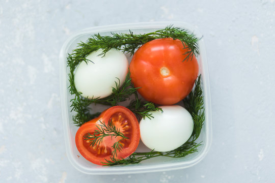 Ripe tomatoes and eggs in container on grey background close up. Healthy diet.