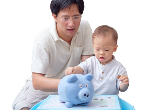 Father and cute Asian 18 months toddler boy putting Thai coin into piggy bank, Happy family money savings concept. Dad teach son on savings & financial planning, isolated on white with clipping path