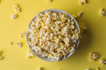 Popcorn in bowl on yellow, top view