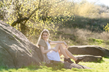 hipster teen sits on the grass outdoor near large stone. Magic landscape