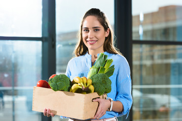 Smiling woman holding box with groceries