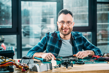 Smiling repairman sitting at his workplace