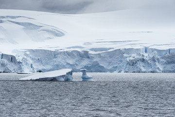 Low clouds over the snow capped mountains and chunks of ice floating at Admiralty Bay, King George...