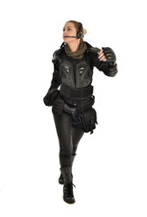 full length portrait of female  soldier wearing black  tactical armour, isolated on white studio background.
