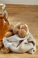 Aromatic oil in a glass jar and bottle with peanuts in bowl on wooden table, close-up, vertical