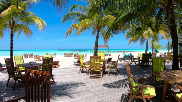 Tropical Terrace With Palm Trees in Maldives in 4K and White Sandy Beach with Turqoise Waters.