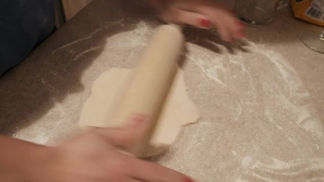 Baker kneading dough with rolling pin on table