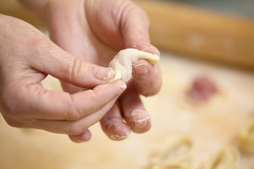  Hands  who prepares  homemade ravioli, pelmeni or dumplings from dough.Traditional Russian dish, national cuisine. Home cooking, handmade. Close-up.