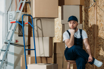 Bored delivery man waiting by stacks of boxes